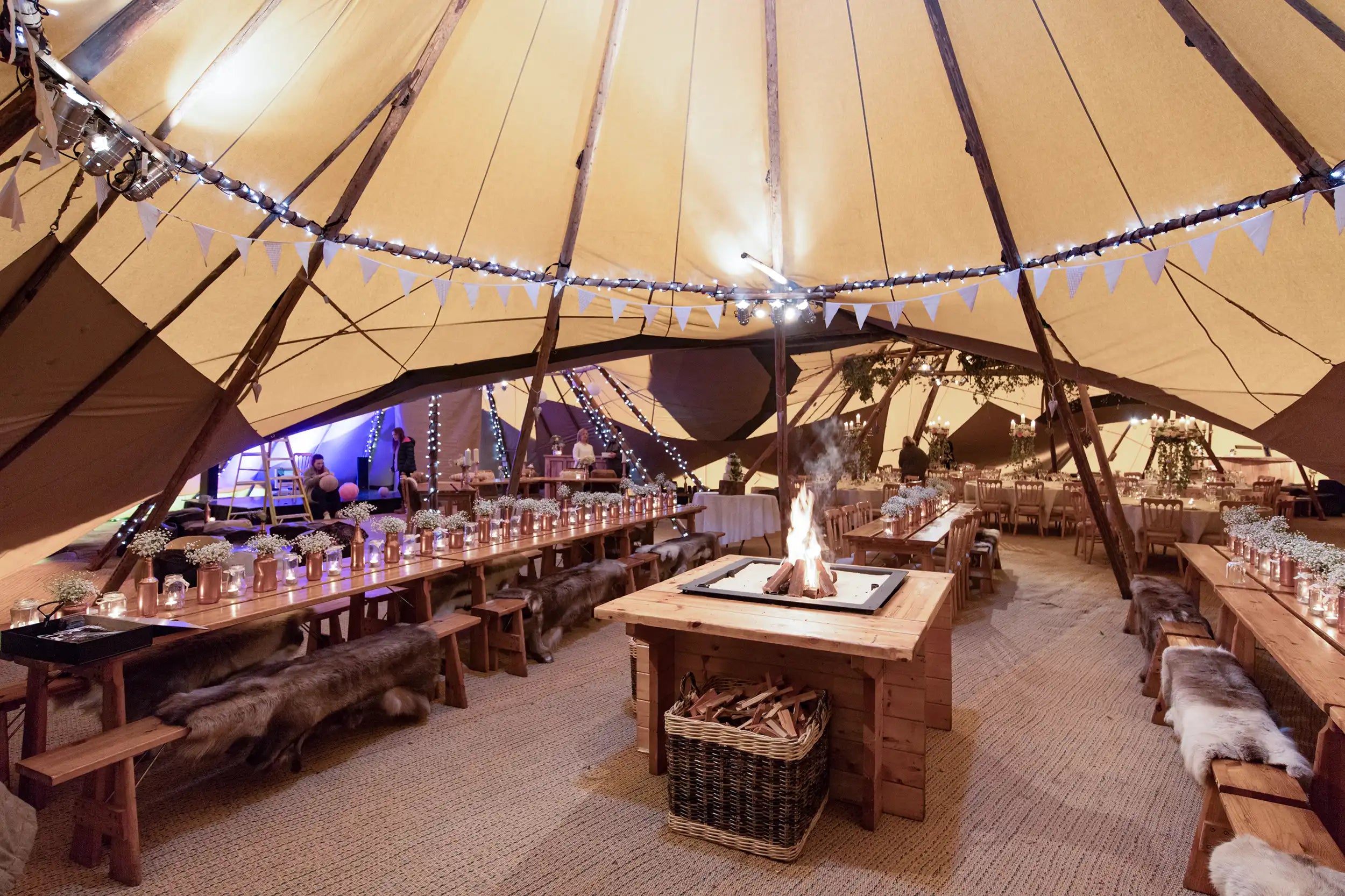 Interior with tables benches and fireplace canvas event tent Nordic tipi Tentipi