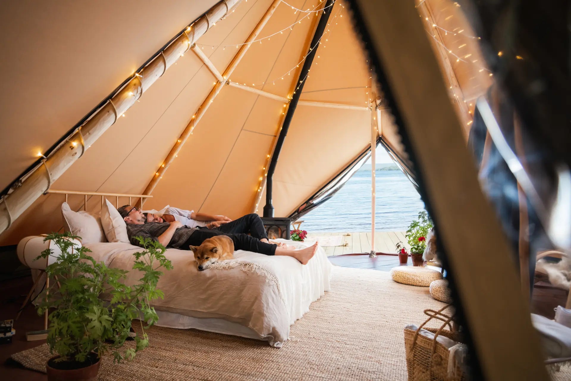 Couple relaxing on the bed in canvas glamping tent Aurum with a view over the lake